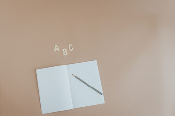 Schulheft mit Stift und ABC auf braunem Hintergrund