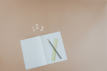Schulheft mit Stift, Lineal und 123 auf braunem Hintergrund