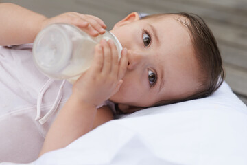 Baby, kid and drinking bottle for nutrition, liquid food and relaxing together on porch at home. Girl, toddler and formula for health or child development in outdoors, feeding and milk for wellness