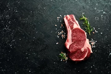 Foto op Plexiglas Dry-aged Raw cowboy on the bone beef meat Steak. On a black stone background. Top view. © Yaruniv-Studio
