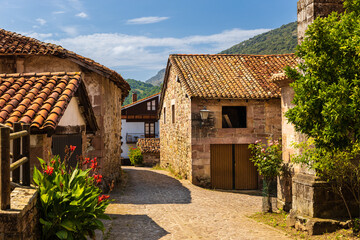 Fototapeta na wymiar Old stone mountain mansions, red roofs, flowers. Carmona, Cantabria, Spain.