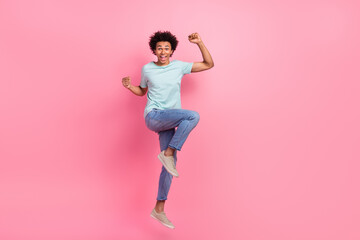 Full length photo of handsome young male raise fists jumping have fun dressed stylish blue garment...