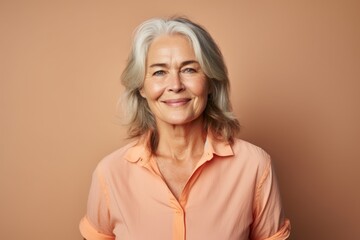 Portrait of smiling senior woman with grey hair on brown background.