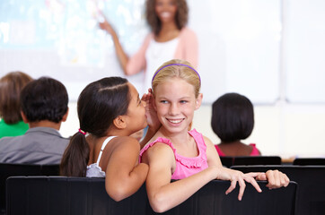 Kids, classroom and whisper in ear for secret, gossip or communication in lesson at school. Little...