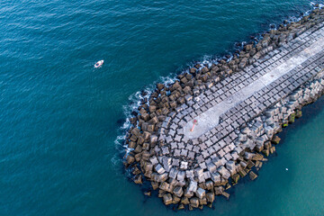 drone aerial view of a boat near a concrete block breakwater. Vila Praia de Ancora, Portugal
