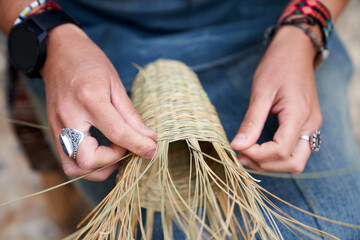 Abobe view of Hispanic woman weaving a basket with esparto fibers. Manual work, tradition and...