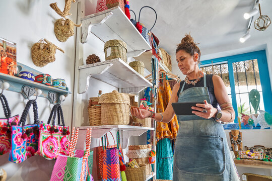 Female Hispanic souvenir shop owner taking inventory with digital tablet