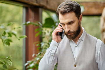 handsome concentrated leader with beard in sophisticated attire talking by phone, business concept