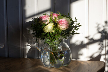 Pastell Blumenstrauß von weißen und rosa Rosen angeleuchtet von der Winter Sonne draussen mit dem Schatten der Sprossenfenster