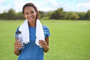 Woman, portrait and happy on grass with water bottle for exercise, training or workout on sports...