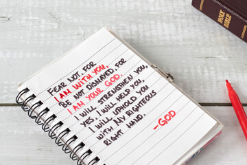 Fear not I am with you, inspiring biblical verse quote handwritten in notebook with holy bible on...