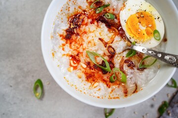 Homemade Asian Chinese style Congee with soft boild egg fried shallots and spring onions