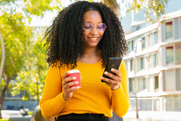 Young African American woman smiling and typing with a smartphone application.