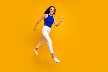 Fototapeta na wymiar Full length photo of adorable pretty lady dressed blue top jumping hurrying empty space isolated yellow color background