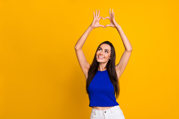 Photo of funky dreamy lady dressed blue top showing arms heart looking empty space isolated yellow...