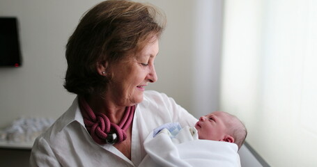Newborn baby infant being held by grand-mother, real life and authentic
