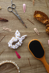 Wooden hairbrush, scissors and various headbands, hair clips and scrunchies on wooden background. Flat lay.