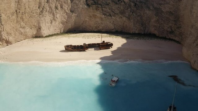 Aerial drone view of boats and tourists at Navagio Shipwreck beach Zakynthos, people  swimming in turquoise waters druing summer in Greece