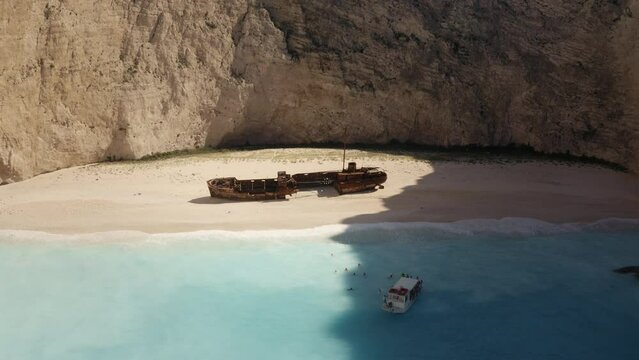 Aerial drone view of Navagio Shipwreck beach Zakynthose Greece, boats and tourists in turquoise waters during a warm summer day