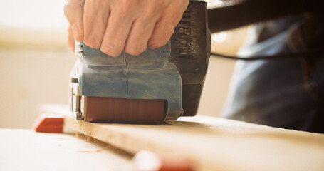 Closeup shot of a carpenter sanding wood with a belt sander. - 707863884
