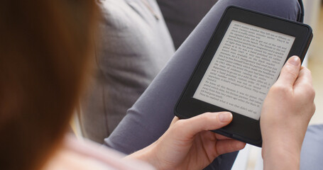 Woman reading an ebook on a reader with an e-ink display - 707864264