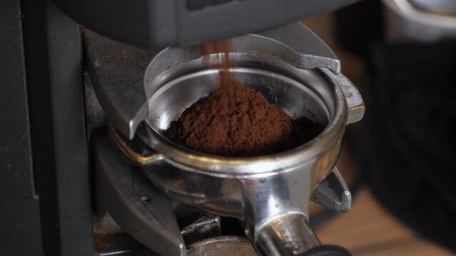 Close-up of a barista tempering freshly ground coffee with a tempera in a coffee shop. The process of making espresso.