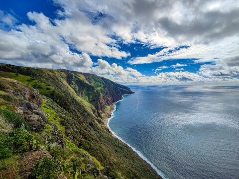 Beautiful scenic view of a colorful Atlantic Ocean cliff coastline. Green cliffs, blue water, sky and clouds. Ponta do Pargo, Madeira island, Portugal