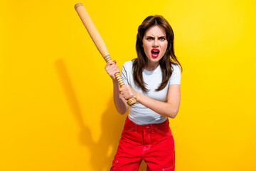 Portrait of angry aggressive girl with retro hairdo wear white t-shirt threatens you with baseball bat isolated on yellow color background