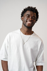Portrait of a smiling young african man wearing white t-shirt standing over gray background