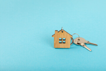 Obraz na płótnie Canvas Keychain in the shape of a house with a key ring on a textured background. Concepts for real estate and moving home or renting property. Buying a property. Mock-up keychain house shaped.