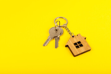 Keychain in the shape of a house with a key ring on a textured background. Concepts for real estate and moving home or renting property. Buying a property. Mock-up keychain house shaped.