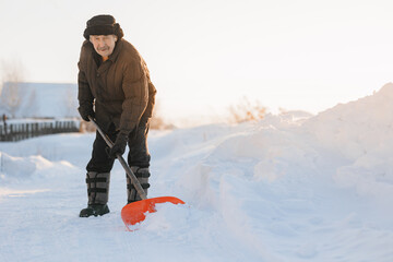 Elderly man cleaning snow with shovel after snowstorm, sunlight © Parilov