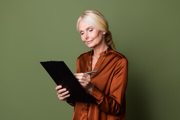 Photo portrait of lovely senior lady writing pen documents dressed stylish brown silk garment isolated on khaki color background