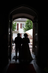 This poignant image captures the silhouette of a newlywed couple standing at the entrance of a...