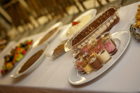 This photograph showcases a sumptuous dessert buffet, inviting guests to a sweet ending of their meal. The image is angled to focus on a variety of desserts, from layered parfaits in glass jars to