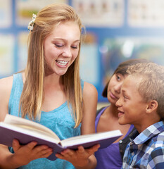 Children, tutor and reading a book in classroom for knowledge, learning or education with happiness. Group, student and scholar at school with study, textbook and smile with teacher and diversity