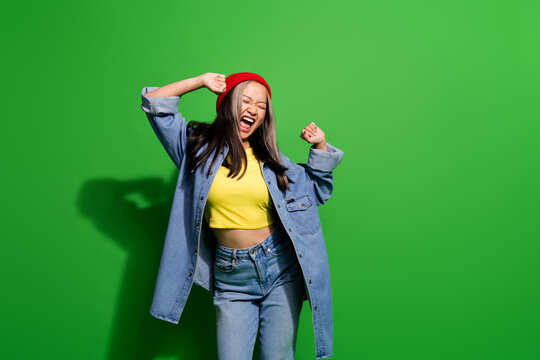 Photo portrait of pretty young girl dancing have fun sing loud energetic dressed stylish denim outfit isolated on green color background