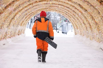 Foto op Plexiglas Worker with shovel walking on festive decorations backgrond, snow removal in winter city © Oleg