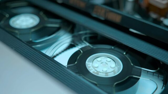 Transparent reels of magnetic tape in a video cassette rotate in a VCR to form an image in a home VCR. Shot in motion. Closeup. Macro. Shallow depth of field