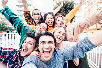 Group of young diverse friends smiling at camera outdoors in the spring time - Multiracial best friends having fun outside - Friendship concept with guys and girls hanging out on city street