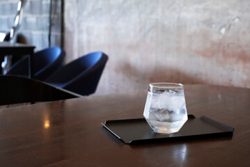 Glass of pure water on wood table in blurred coffee shop background.