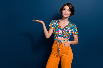 Portrait of young funny woman wear stylish retro garment holding palm look curious at mega sale offer isolated on blue color background