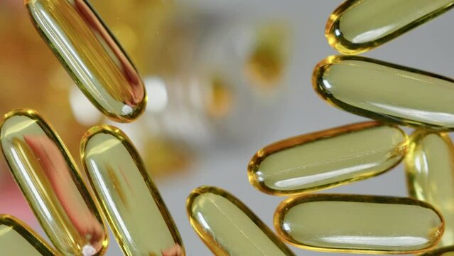 Close up shot pouring omega 3 fish oil capsules vitamine D3 vitamin E capsules on flat surface from a bottle