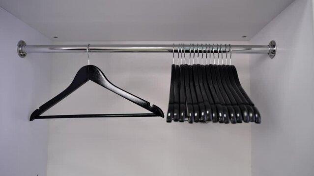 black shiny hangers hang in a clean white closet. empty black wooden clothes hangers on the shop counter. Sale of tramples, sale of clothes. close-up. an empty cabinet in a store after a sale.