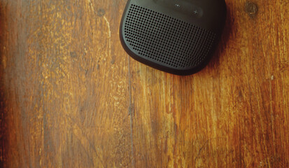 closeup photo of a black wireless speaker on a wooden table - 707924618