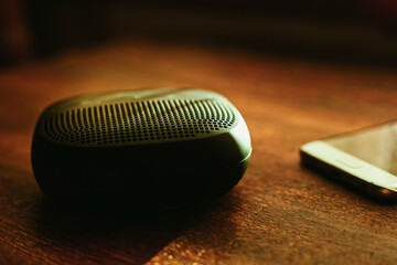 closeup photo of a black wireless speaker on a wooden table - 707924699