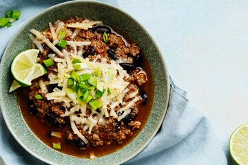 Beef chili con carne with green onions and cheese directly above