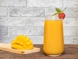 Mango juice in a glass on a wooden background.
