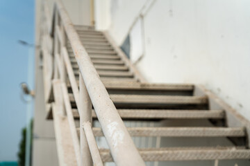The metal with banister stair walkway outside a factory building, using as emergency exit or service route. Close-up and selective focus on handrail part.