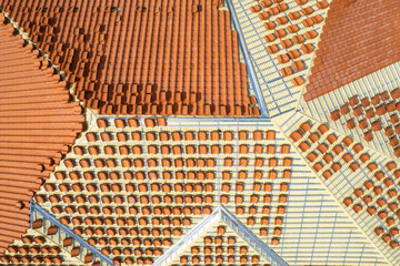 Clay terracotta roof tiles ready to be installed on top of basic corrugated sheet metal roofing. Aerial top view of a residential house under construction.